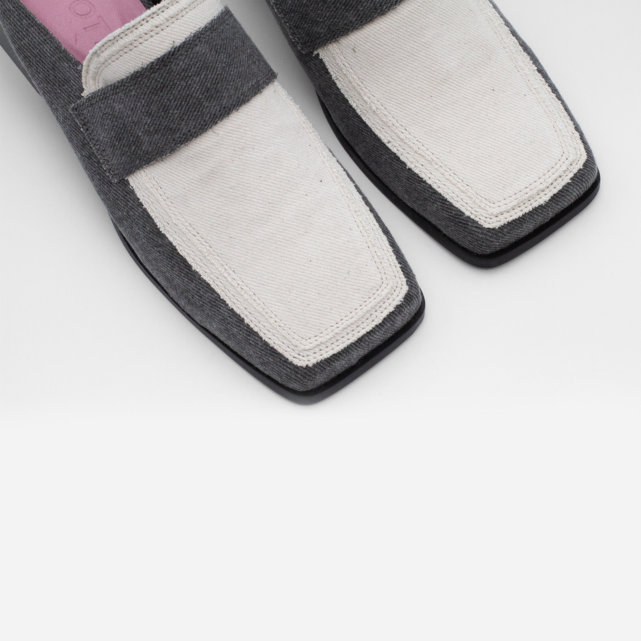 Close-up of vegan denim loafers from SCOTTI with dual textures, featuring white fabric toe caps and grey fabric at the sides and heel. The shoes showcase a square toe design and a pink insole, set against a plain white background.