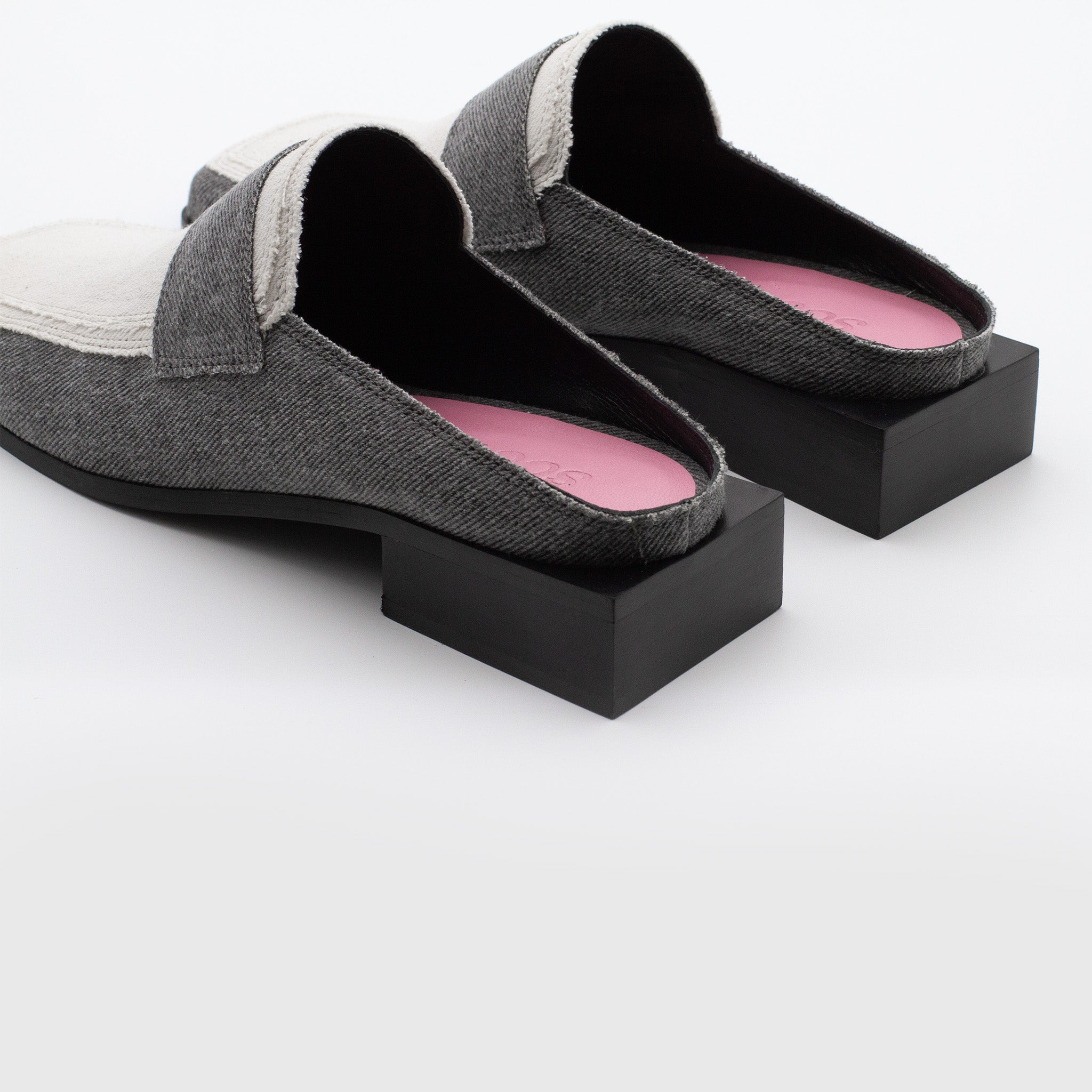 A pair of unique, backless gray SCOTTI loafers with black cube-shaped heels and white toe caps. The interior features vegan-friendly pink lining, and the shoes rest elegantly on a white background